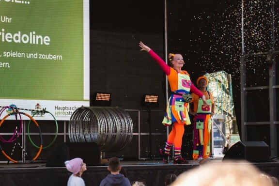 Clown und Kinder beim Familienfest Goldener Reiter mit bunten Kostümen.
